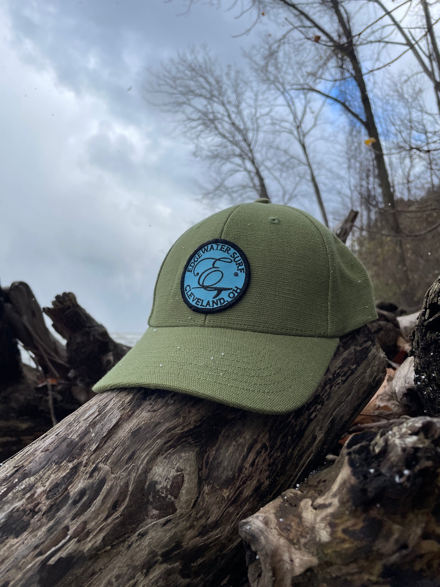 Green cap with a logo on a wooden log against a snowy background