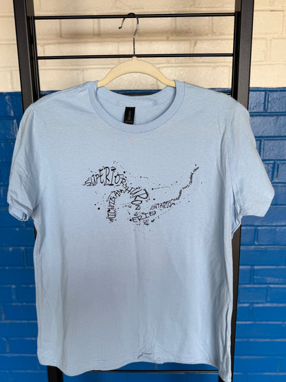 Light blue t-shirt with graphic design on a hanger against a blue brick wall.